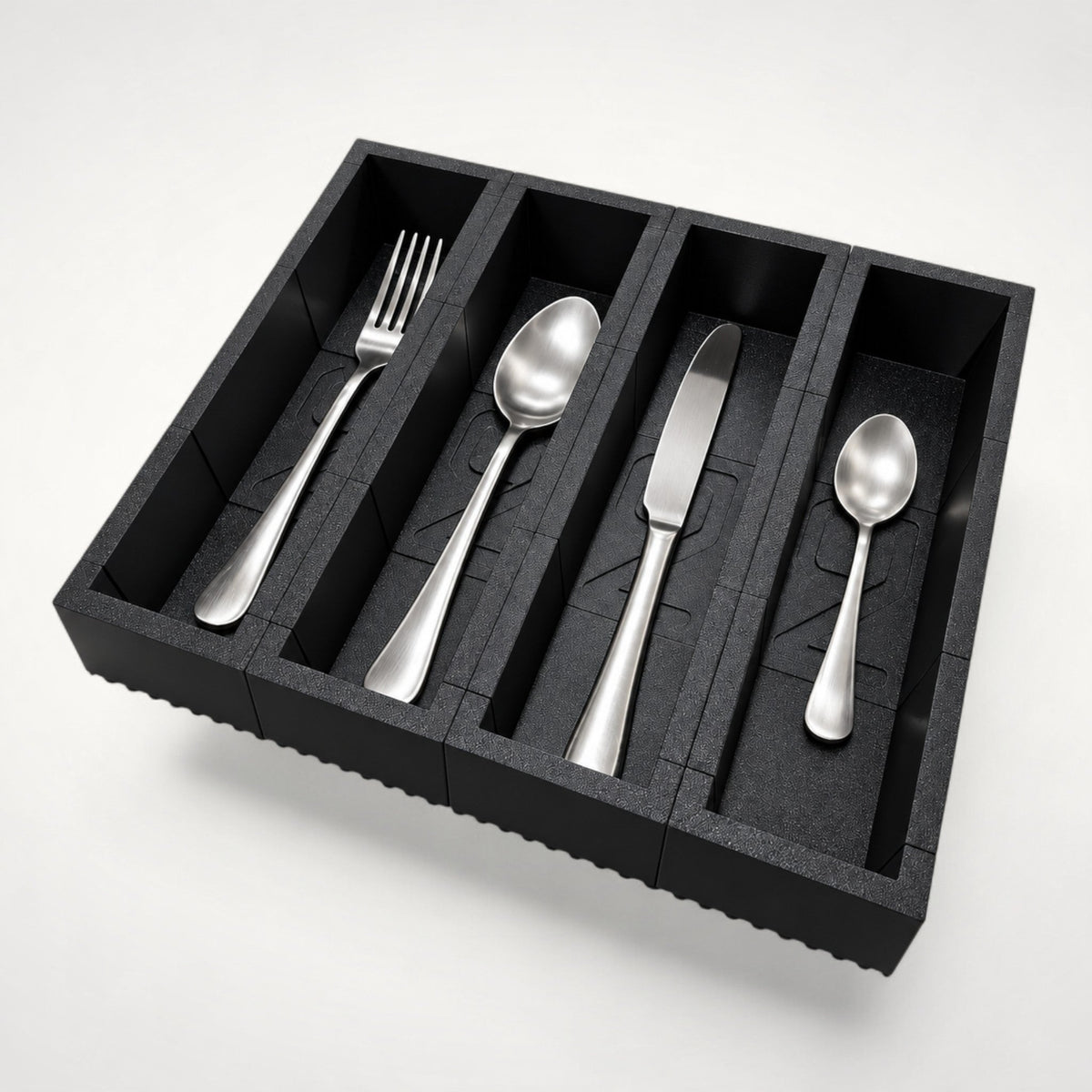 NG Organisers black plastic four-compartment cutlery drawer tray with silver utensils on a white background