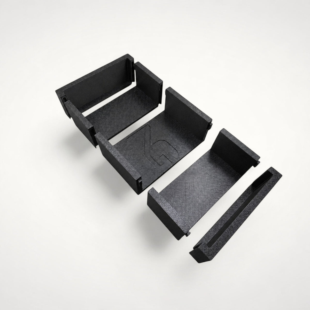 NG Organisers modular storage box components in black, featuring a branded centre piece and interlocking edges.